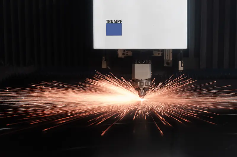 Trumpf fibre laser cutting head with a symmetrical burst of orange sparks